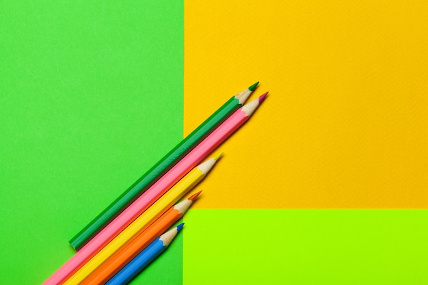 Colorful pencils on a bright green paper background