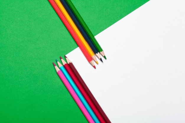 Colorful pencils on a bright green paper 