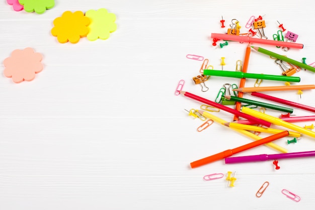 Colorful pencils and felt-tip pens, notepaper and stationery on white wooden background. 