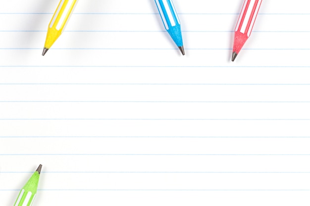 Colorful pencils on notebook lined paper background with copy space. Back to school, education, learning concept