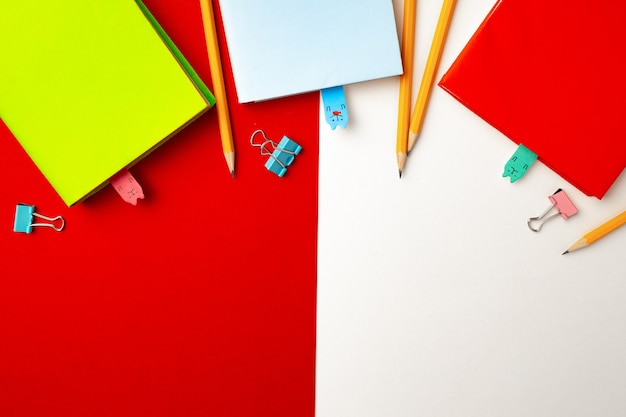 Colorful pencils and notepads on paper background top view, copy space