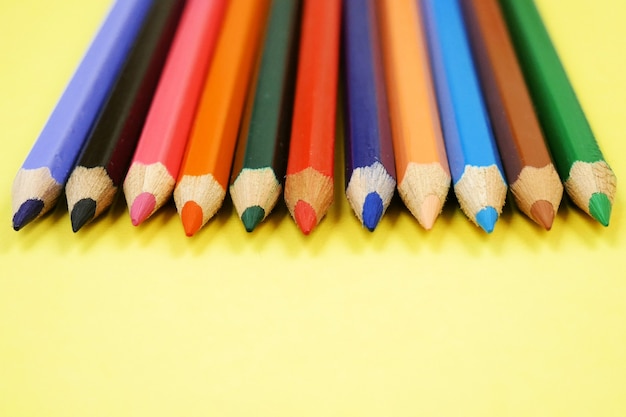 Colorful Pencils raw on yellow background, closeup