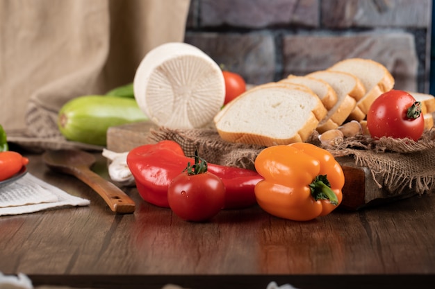 Colorful peppers on the wooden table with cheese and bread