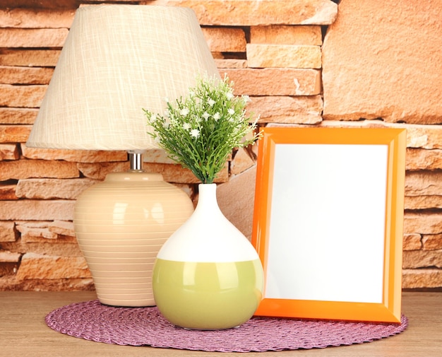 Photo colorful photo frame lamp and flowers on wooden table on stone wall background