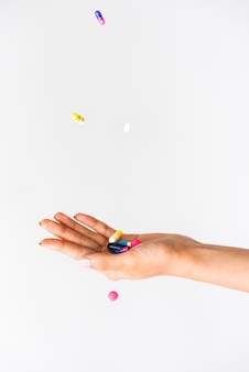 Pillole colorate che cadono dall'alto su un palmo Foto Premium