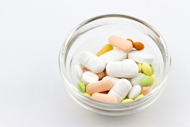 Colorful pills and medical capsules in a bowl.