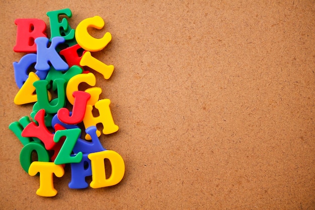 Colorful plastic alphabet letters scrambled on a wooden background