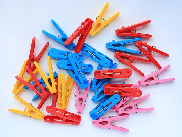 Clothespins di plastica variopinti su priorità bassa bianca.