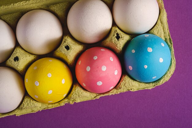 Photo colorful polka dot easter eggs in egg tray on purple violet