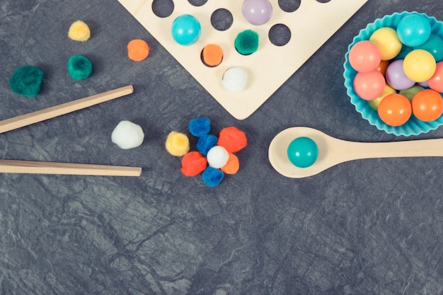 Colorful pompoms and balls as accessories using for playing and development of kids motor skills coordination and logical thinking