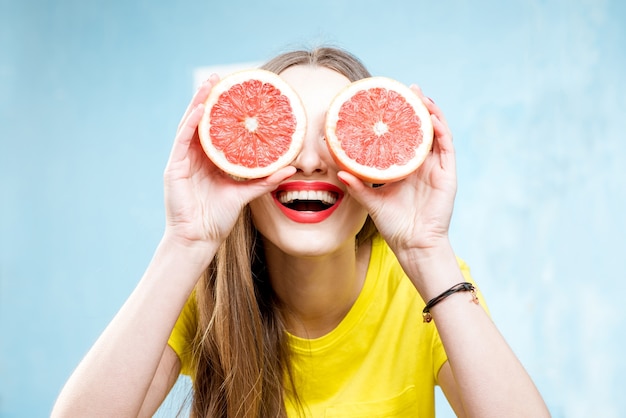 Photo colorful portrait of a beautiful woman grapefruit slices on the yellow background
