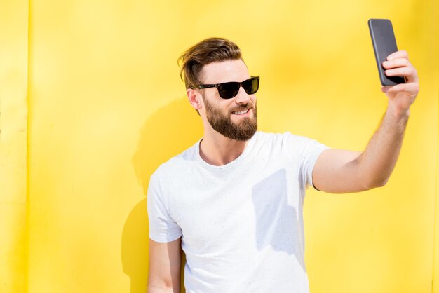 Colorful portrait of a handsome man dressed in white t-shirt on the yellow background