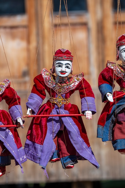 Colorful puppets in a tourist stall on the street market in Burma. Souvenir items for sale in Myanmar. Handmade dolls hanging on display store