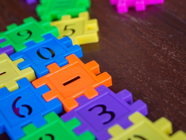 Numero di plastica del puzzle variopinto del puzzle sulla tavola di legno. concetto di educazione e apprendimento della matematica