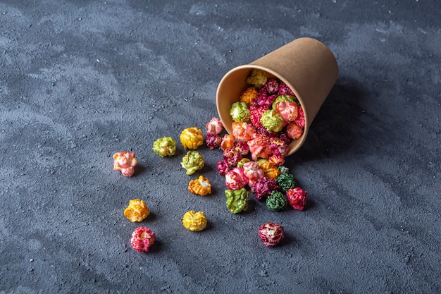 Colorful rainbow caramel candy popcorn on dark background. Cinema snack concept. Food for watching movie and entertainment. Copy space for text, flat lay.