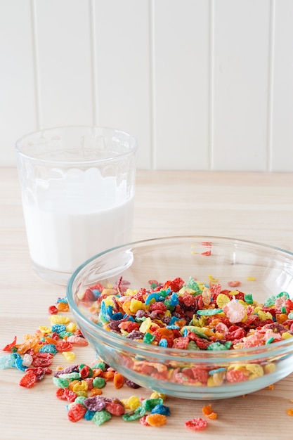 Colorful rice cereal, milk and red apple. Healthy quick breakfast. Wooden background. Copy space. Vertical. Selective focus.