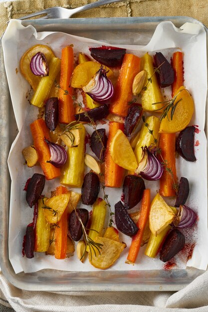 Colorful roasted vegetables on tray with parchment. Mix of carrots, beets, turnips, rutabaga