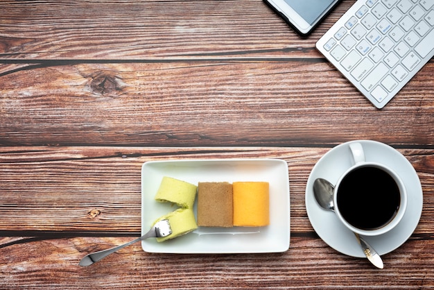 Colorful roll cakes and coffee on pattern wood background