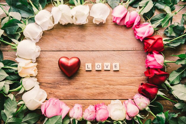 Foto rose colorate allineate su un pavimento di legno con cuore e parola