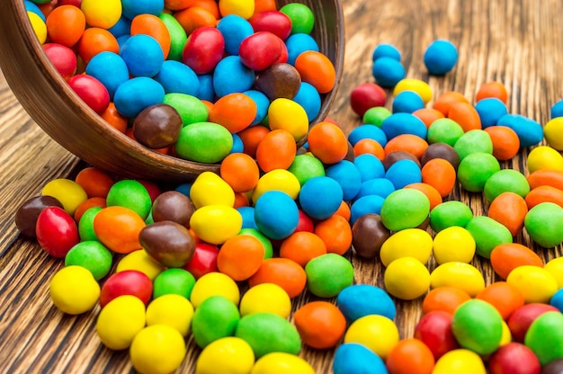 Colorful round candies scattered from bowl on the table Close up