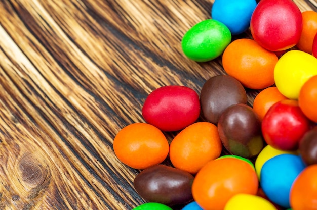 Colorful round candies on wooden table Top view