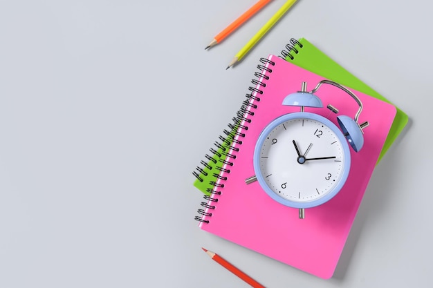 Colorful school supplies and alarm clock on blue background