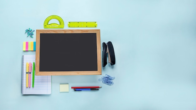 Colorful school supplies and chalkboard on light blue surface Back to school education concept Banner image