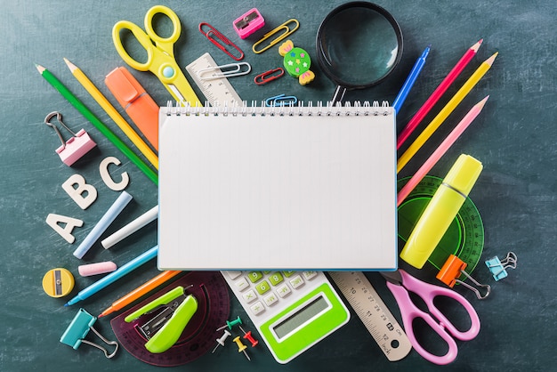 Colorful school supplies, stationary on chalk board.