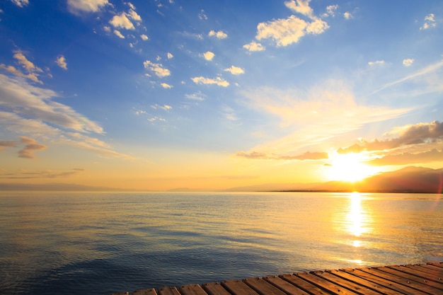 Colorful sea beach over mountains sunrise with deep blue sky and sunbeams natural background Bright sky in the rays of the orange sun