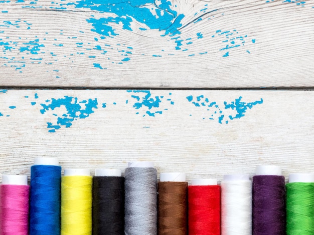 Colorful sewing threads on the old wooden background Top view