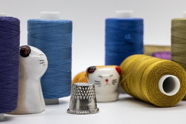 Photo colorful sewing threads with ceramic cat figurines and thimble