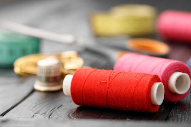 Colorful sewing utensils on black wooden surface