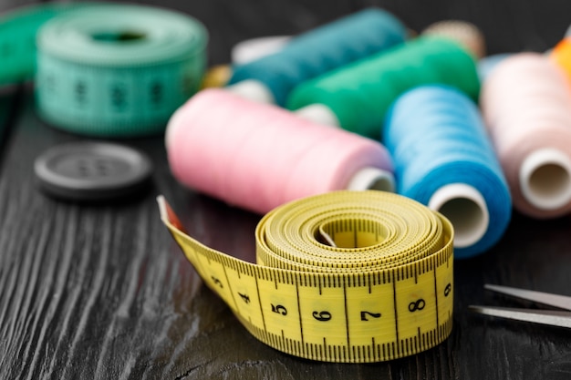 Colorful sewing utensils on black wooden surface