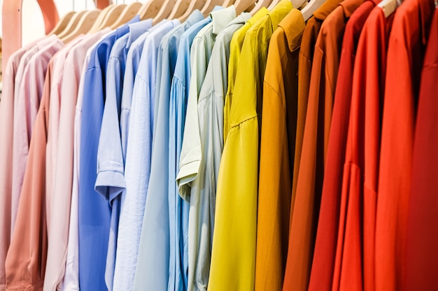 Colorful shirts on the hangers in the store close up