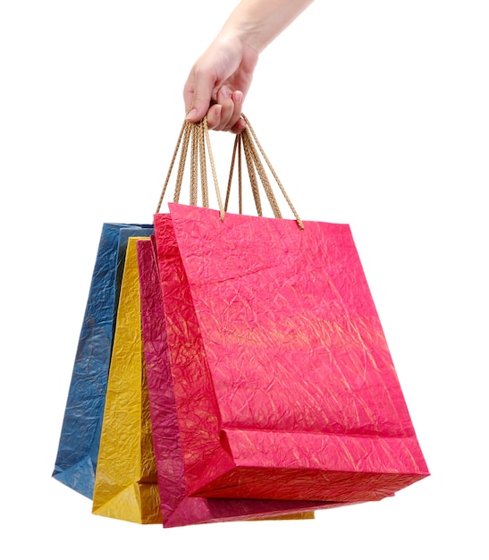 Colorful shopping bags in female hand, on white