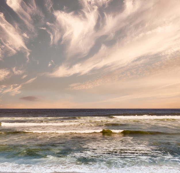 Colorful sky sea waves and beautiful beach view with tides and currents under a natural horizon on a cold morning with copy space A quiet and serene ocean scene in nature during the evening