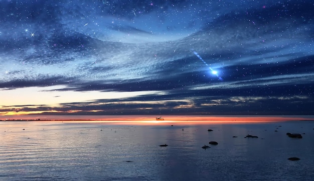 Colorful sky on sunset at sea water reflection gold sun beam\
and starry sky star fall flares