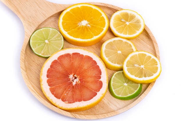 Colorful slices of citrus fruits on a wooden tray.