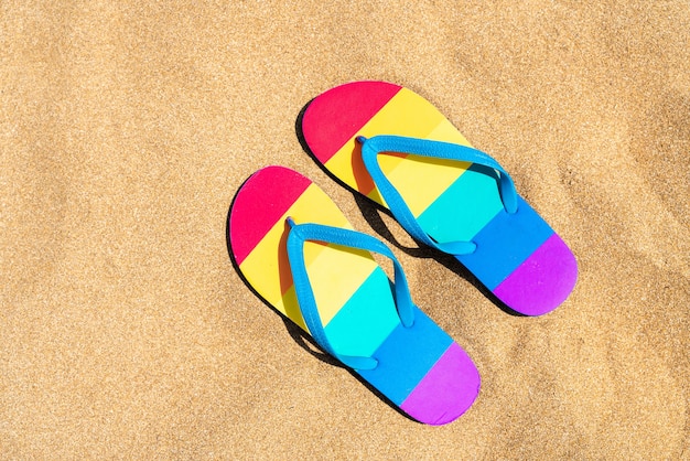 colorful slippers on the beach on a summer day  gay pride flag  flip flops