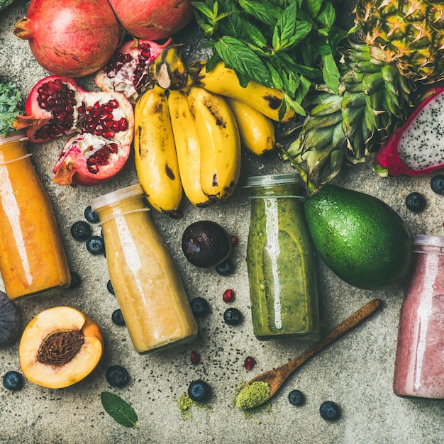 Frullati colorati in bottiglia con raccolto quadrato di frutta fresca tropicale