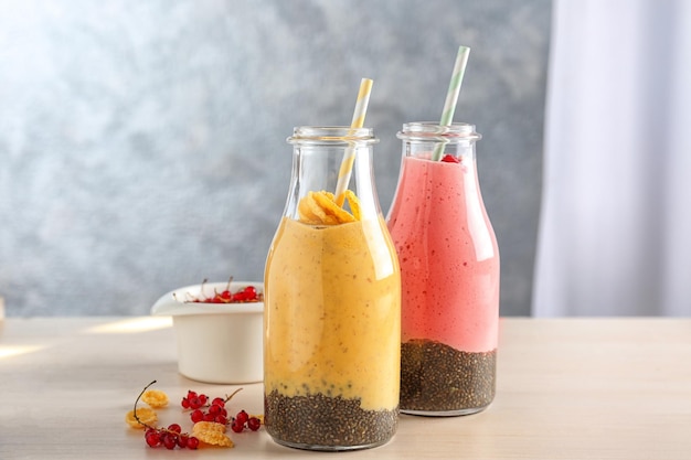 Colorful smoothies with chia seeds in bottles on table