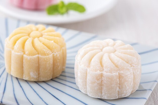 Photo colorful snow skin moon cake sweet snowy mooncake traditional savory dessert for midautumn festival on bright wooden background close up lifestyle