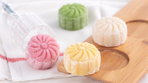 Photo colorful snow skin moon cake sweet snowy mooncake traditional savory dessert for midautumn festival on bright wooden background close up lifestyle