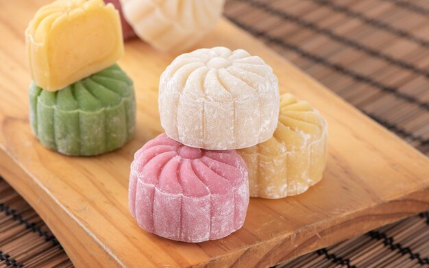 Photo colorful snow skin moon cake sweet snowy mooncake traditional savory dessert for midautumn festival on bright wooden background close up lifestyle