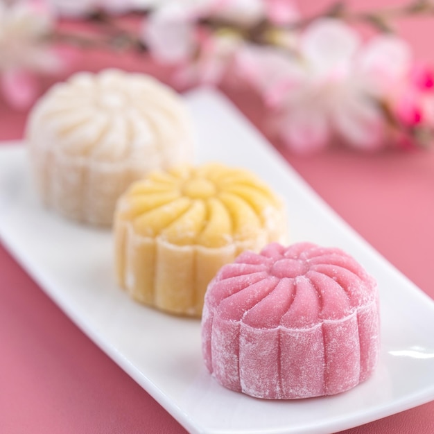 Photo colorful snow skin moon cake sweet snowy mooncake traditional savory dessert for midautumn festival on pastel pale pink background close up lifestyle