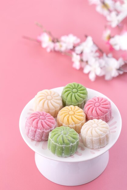 Photo colorful snow skin moon cake sweet snowy mooncake traditional savory dessert for midautumn festival on pastel pale pink background close up lifestyle