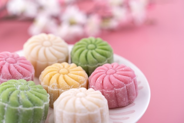 Photo colorful snow skin moon cake sweet snowy mooncake traditional savory dessert for midautumn festival on pastel pale pink background close up lifestyle