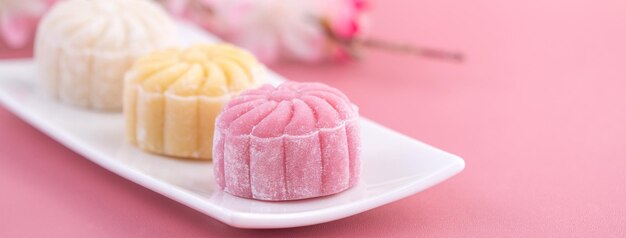 Photo colorful snow skin moon cake sweet snowy mooncake traditional savory dessert for midautumn festival on pastel pale pink background close up lifestyle