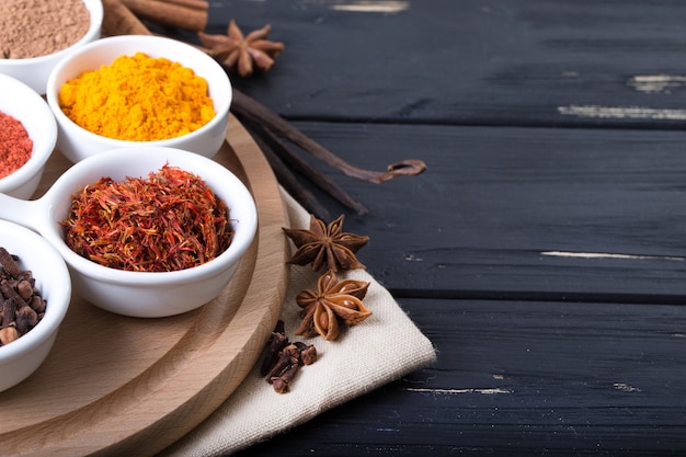 Colorful spices in ceramic containers on a dark background