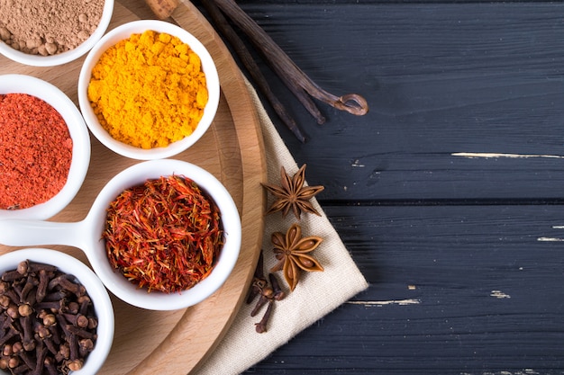 Colorful spices in ceramic containers on a dark